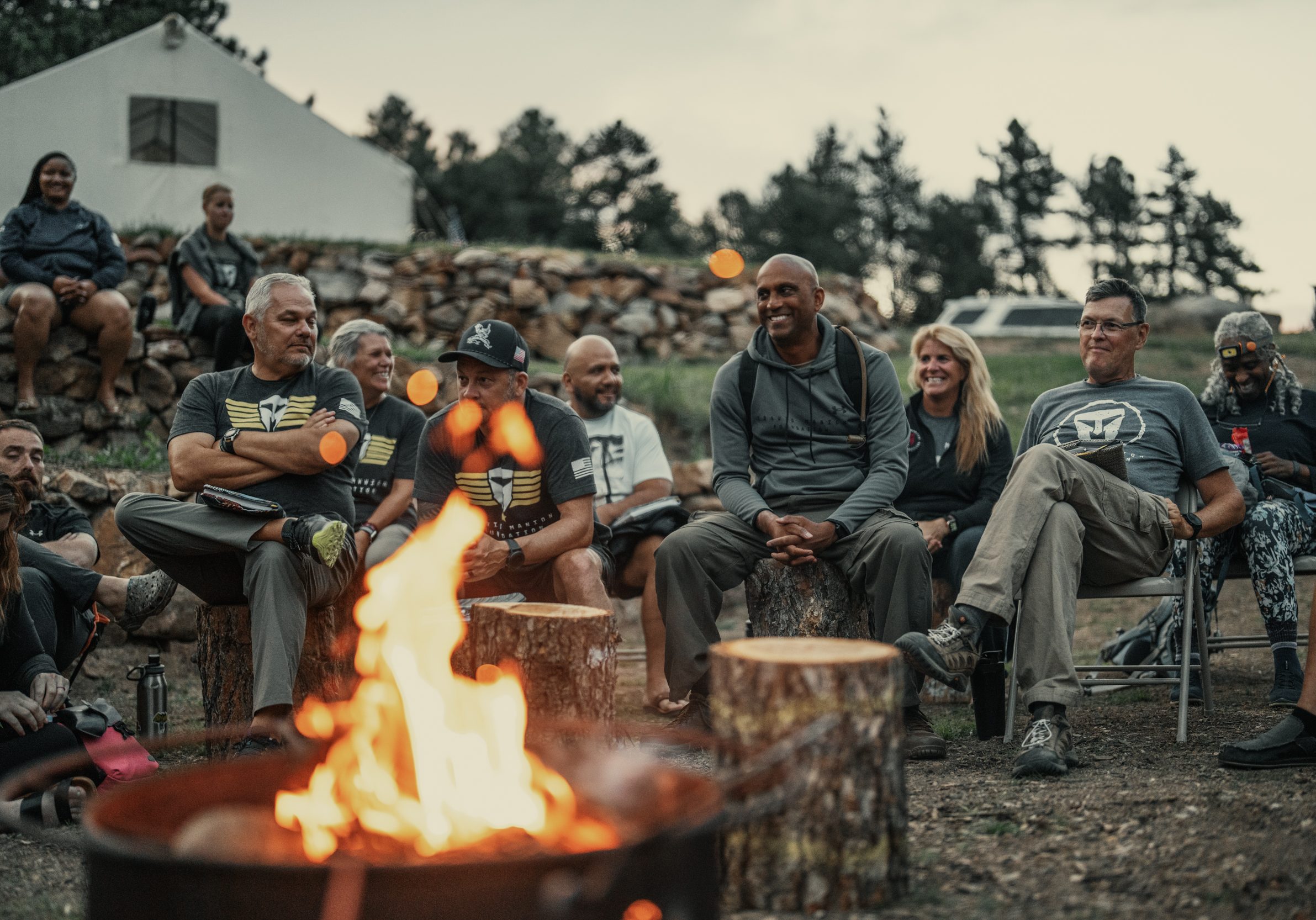 Group of people gathered around a campfire during a Big Fish Foundation outdoor event.